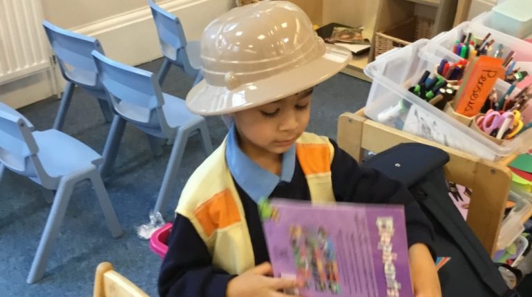 Child wearing a plastic hat as he reads a book