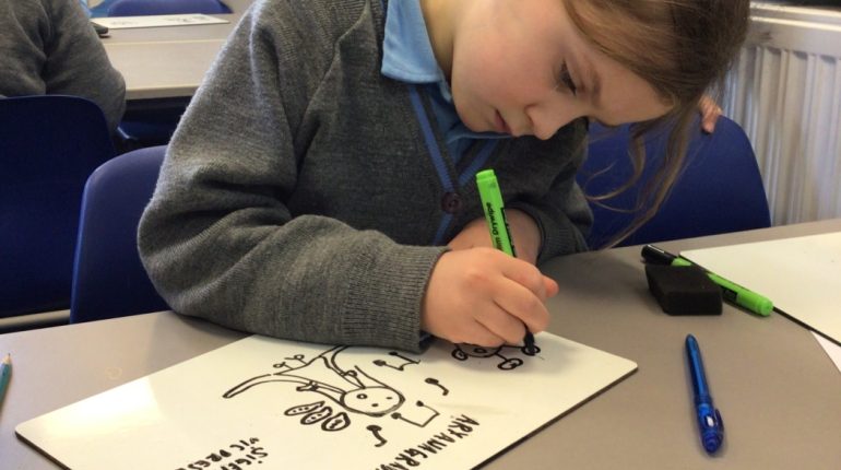 child drawing onto a small whiteboard